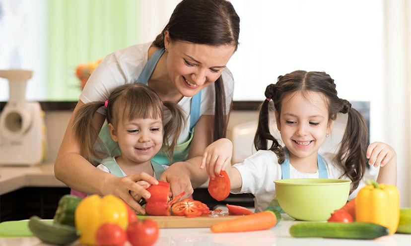 Woman and two young girls chopping vegetables together