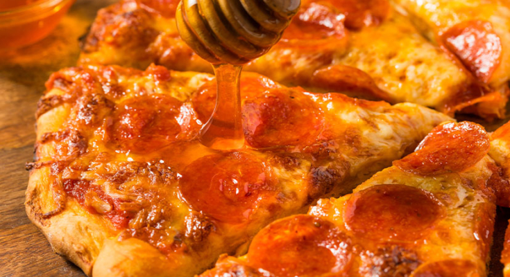 Pizza with honey being drizzled on it
