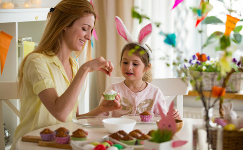 woman and child wearing bunny ears decorating baked goods for Easter