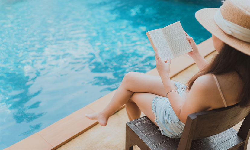 Woman next to pool reading a book in a chair
