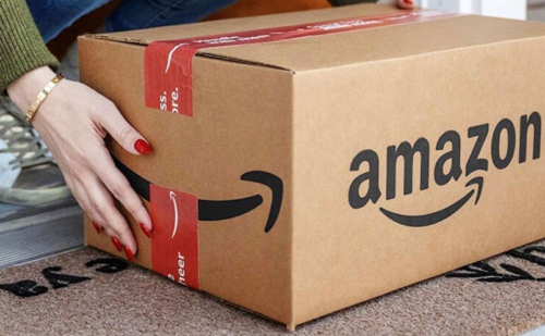An Amazon box being lifted off a porch