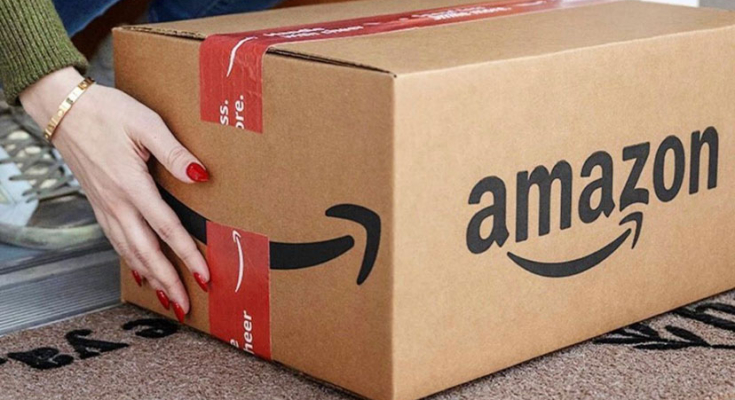 An Amazon box being lifted off a porch